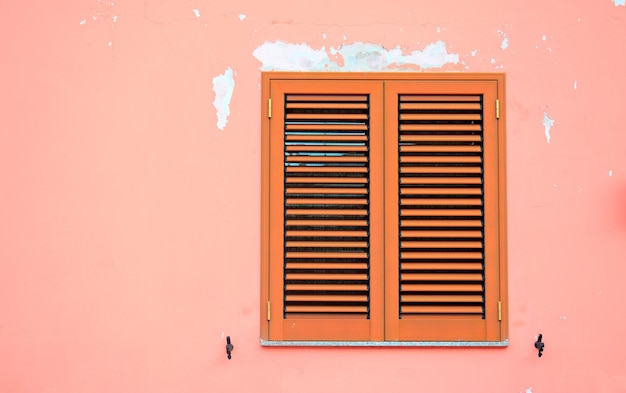 Contraventanas marrones en una pared rosa