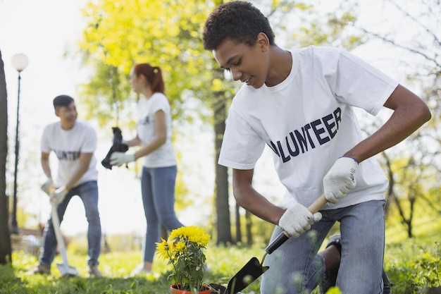 Contribuição para a comunidade. Ângulo baixo de um voluntário masculino atraente olhando para baixo enquanto usa ferramentas de jardim