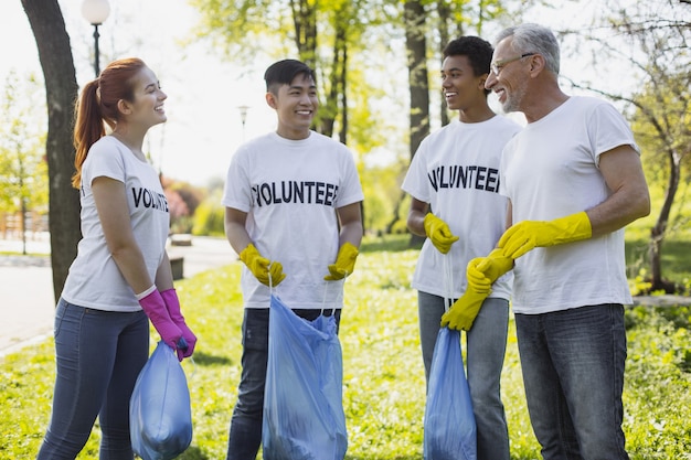 Contribuição para a comunidade. Voluntários exuberantes discutindo e usando luvas