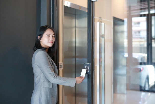 Control de acceso a la puerta: mujer joven oficial que sostiene una tarjeta de acceso para bloquear y desbloquear la puerta de acceso.