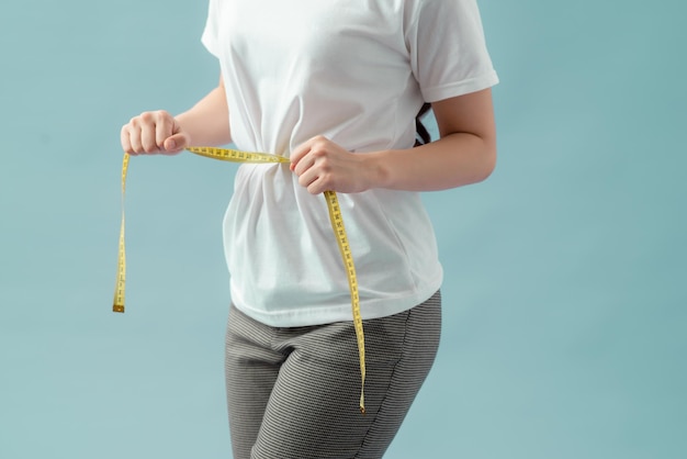 Control de peso del cuidado corporal saludable de las mujeres midiendo la grasa de la cintura usando cinta métrica o cinta métrica