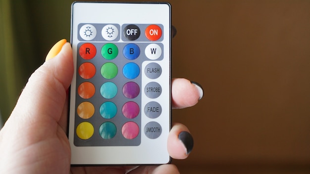 Foto control remoto para cambiar colores en mano sobre fondo borroso