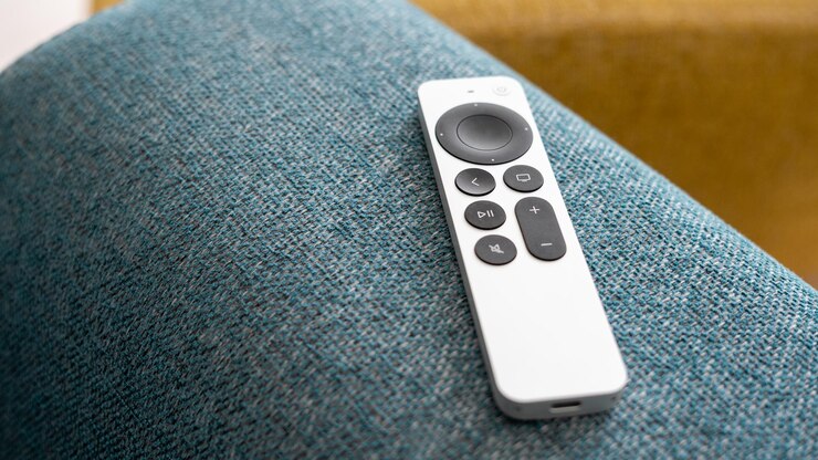 Un control remoto de TV inteligente en un brazo plegado de sofá azul