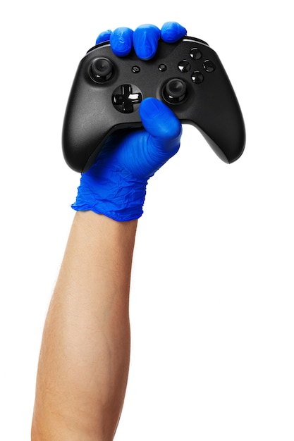 Controlador de consola de videojuegos en manos enguantadas de jugador. Juegos durante el aislamiento en casa, coronavirus