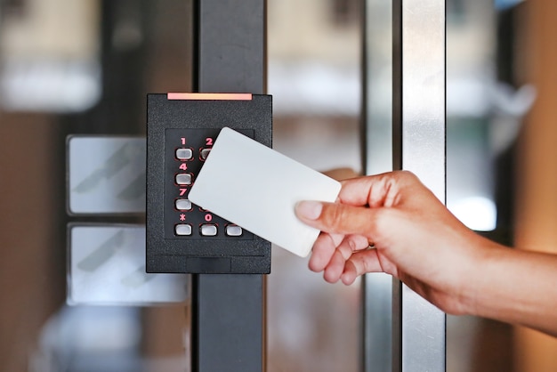 Controle de acesso de porta - jovem mulher segurando um cartão-chave para bloquear e destravar a porta.