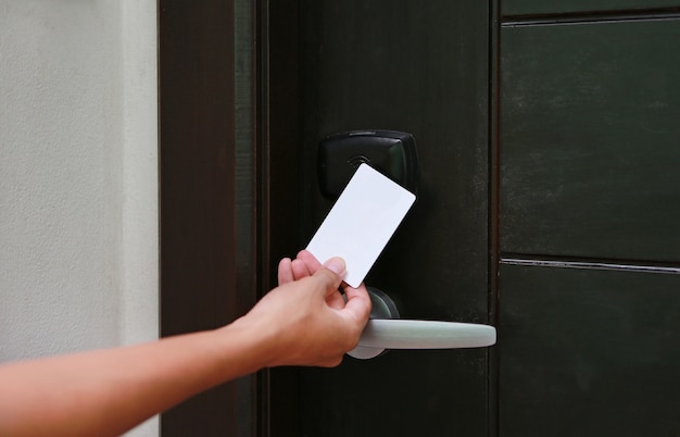 Controle de acesso de porta - jovem mulher segurando um cartão-chave para destravar a porta