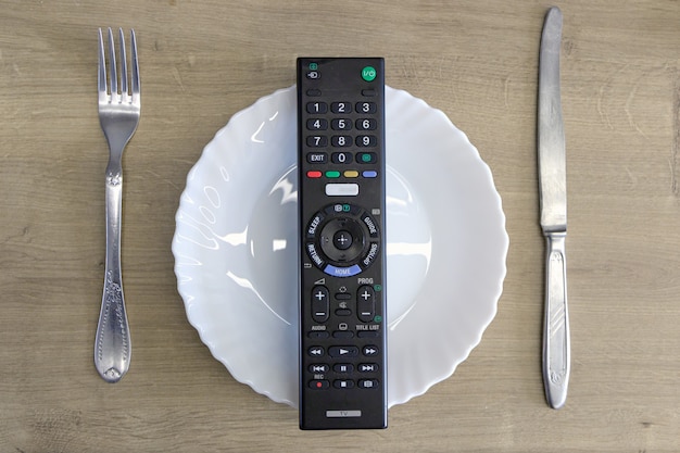 Controle remoto da TV em um prato com talheres