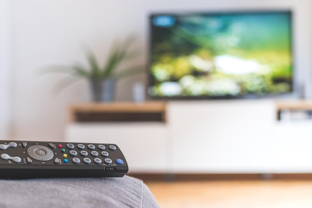 Foto controle remoto no sofá transmitindo em uma smart tv