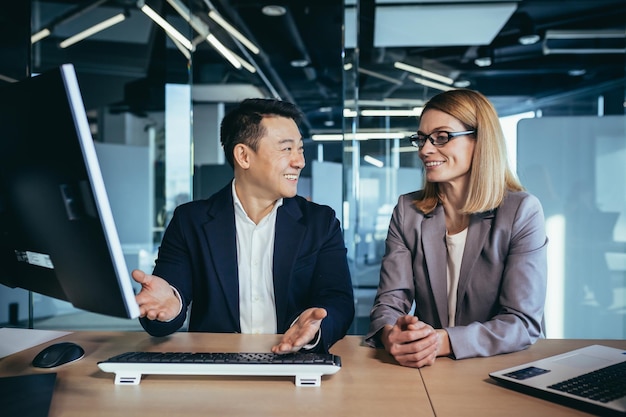 Conversa amigável de colegas de trabalho no escritório homem asiático e mulher de negócios se comunicam durante o intervalo do trabalho com uma xícara de café e um copo de trabalho em equipe e amizade de trabalhadores de água