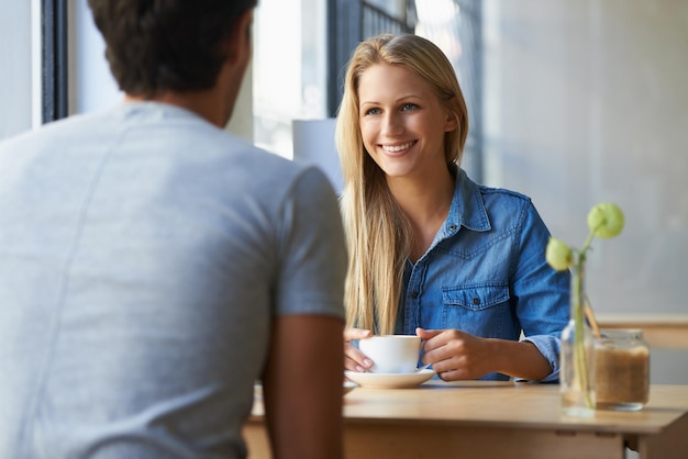 Conversa sobre café Foto recortada de um jovem casal afetuoso em um café