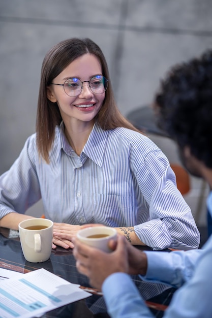 Conversação. Mulher jovem e bonita em óculos conversando com seus colegas