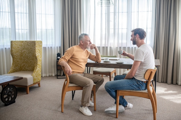 Conversacion. Dos hombres sentados a la mesa, tomando té y hablando