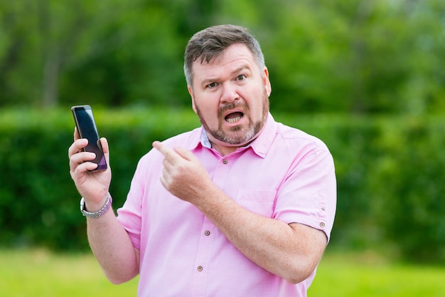 Conversación emocional de un hombre en un teléfono inteligente móvil Hombre adulto con incredulidad e ira por hablar