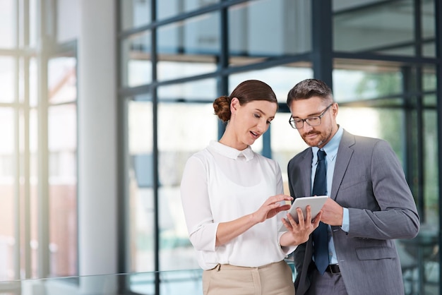 Conversando com um colega de confiança foto recortada de dois empresários olhando para um tablet digital no escritório