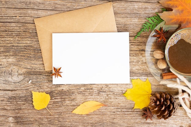 Convite de outono de cartão branco, folhas e café em fundo de madeira de outono