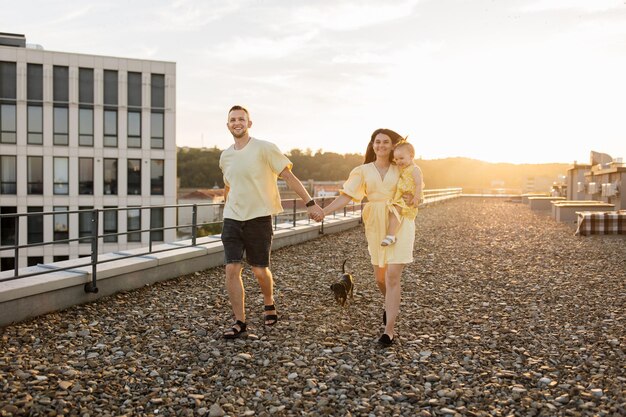 Foto cónyuges jugando con su hija y su perro en la terraza de la construcción