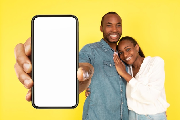 Cónyuges Negros Felices Mostrando Teléfono Grande Pantalla Vacía Sobre Fondo