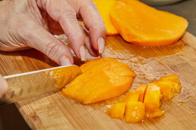 Foto cook corta a manga suculenta em rodelas para fazer a salada.