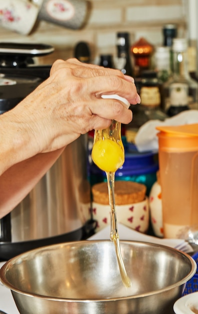 Cook fügt ein Ei in die Schüssel mit den Zutaten, um das Gericht zuzubereiten