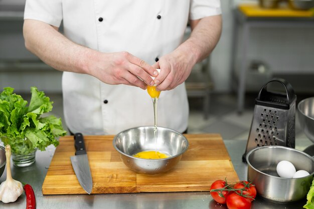 Cook rompe un huevo. Yema de huevo cayendo en el bol