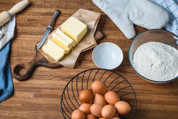 Cook schneidet Butter auf dem Tisch mit Zutaten.