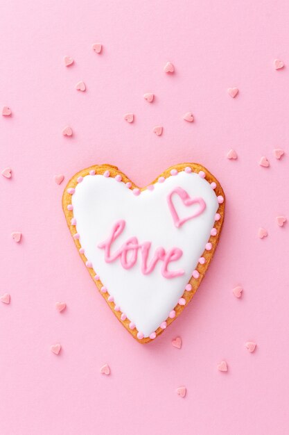 Cookie em forma de coração com a palavra AMOR em fundo rosa