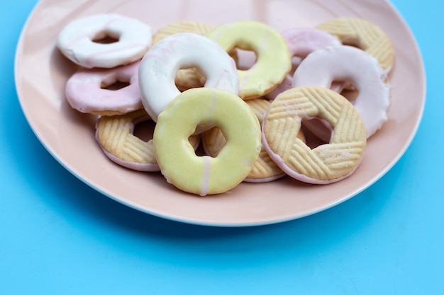 Cookie formas donut en placa sobre fondo azul.