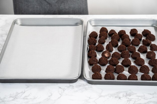 Cookie-Teig mit einer kleinen Teigschaufel in ein mit Pergamentpapier ausgelegtes Backblech schöpfen, um weiße Pfefferminz-Schokoladenkekse zu backen.