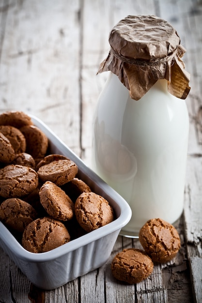 Cookies de amêndoa de merengue em uma tigela e uma garrafa de leite