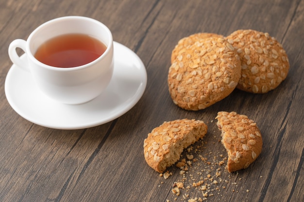 Cookies de aveia com sementes e cereais perto de uma xícara de chá preto branco