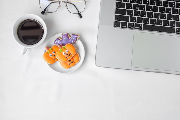 Cookies de Halloween, café quente e computador portátil em fundo branco. Feliz Dia das Bruxas, compras online, Olá, outubro, outono, conceito festivo, festa e feriado