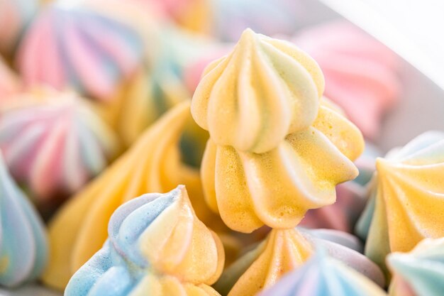 Cookies de merengue de unicórnio multicoloridos em um prato branco.