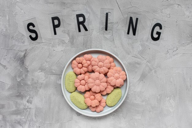 Cookies de palavra e flor de primavera em um prato em um cinza