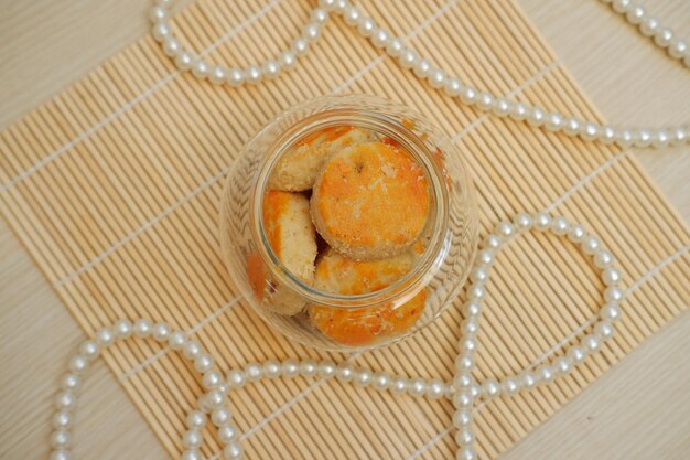Foto cookies em um frasco de vidro em um tapete de bambu com pérolas