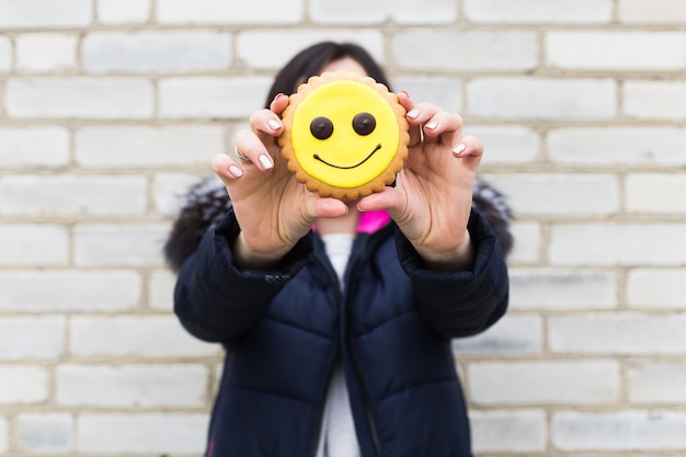 Foto cookies in form eines emoticon. fröhliches mädchen mit keksen.