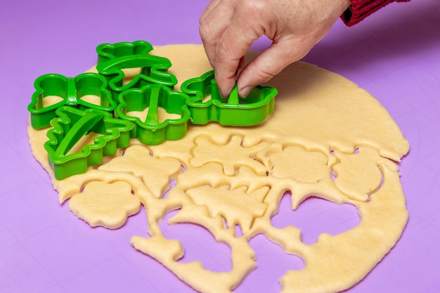 Cookies in Form verschiedener Figuren herstellen. Frau Konditor mit Hilfe von Plastikformen formt aus dem Teig Kekse zum Backen