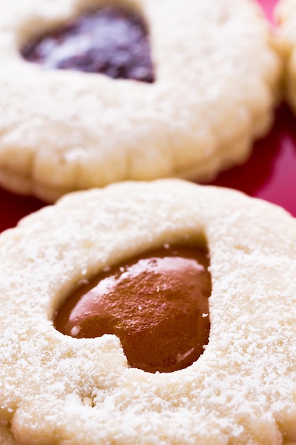 Cookies Linzer Torte na placa vermelha com açúcar de confeiteiro polvilhado por cima.