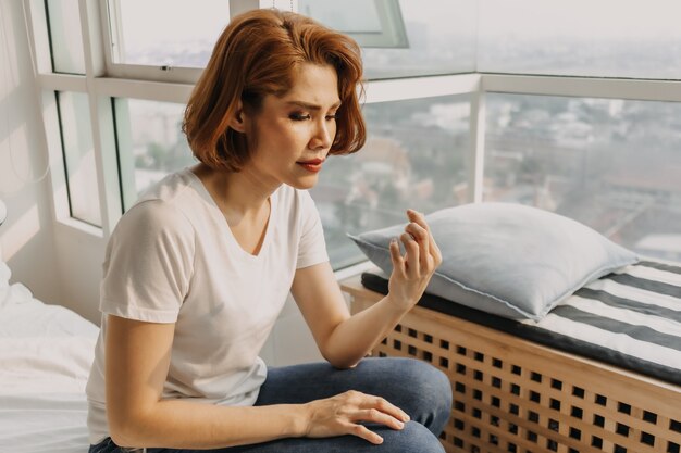 Cool aussehende Frau in Jeans und weißem T-Shirt entspannt sich in ihrer Wohnung