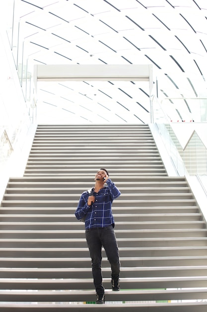 Foto cool chico negro joven en las escaleras hablando por teléfono celular