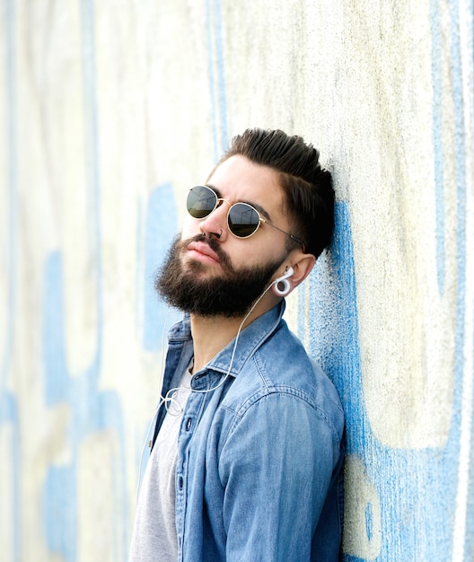 Cool guy con barba escuchando música con auriculares