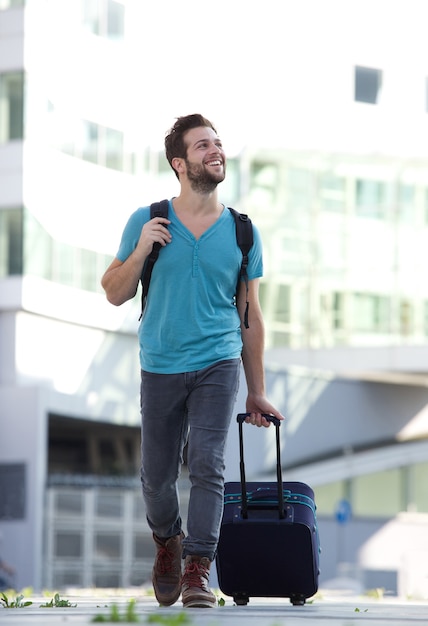 Cool guy sonriendo con maleta y bolso