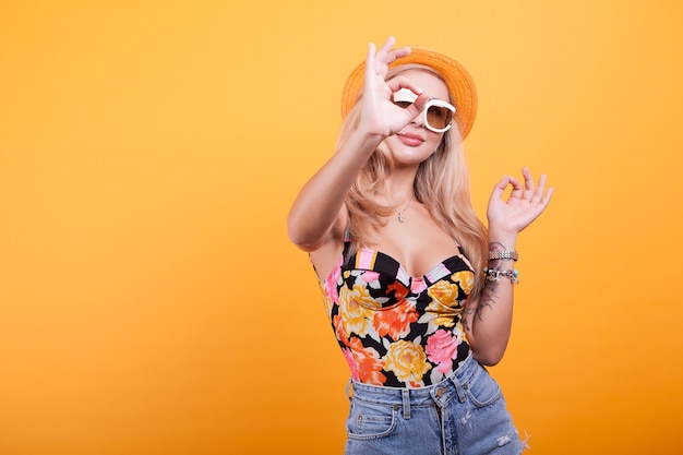 Cool hermosa joven con gafas, en estudio con sombrero sobre fondo amarillo