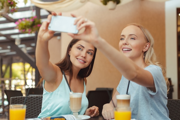 Coole modische Mädchen, die ein Selfie in der Kaffeestube nehmen