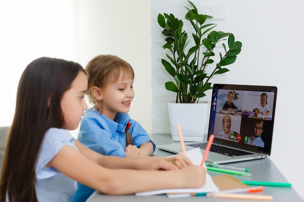 Coole Online-Schule. Kinder lernen zu Hause online mit einem Laptop. Fröhliche junge kleine Mädchen, die Laptop-Computer verwenden, die über ein Online-E-Learning-System lernen. Fern- oder Fernunterricht