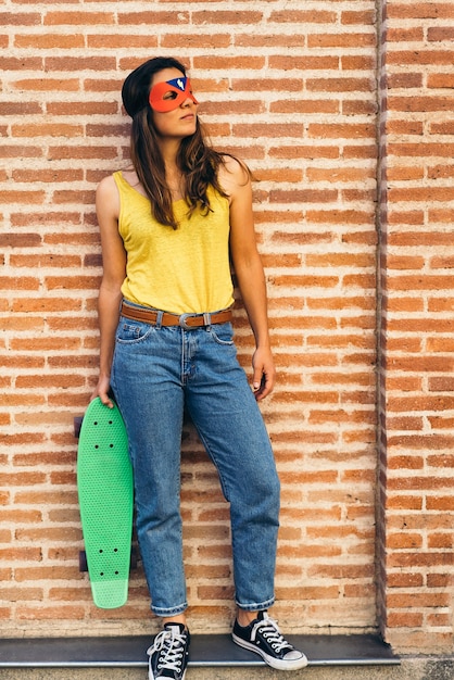 Foto coole und moderne superheldenfrau, die mit skateboard aufwirft.