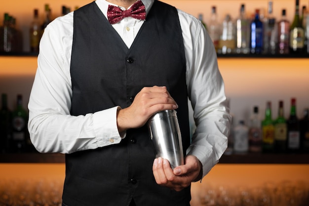 Cooler professioneller Barkeeper, der einen Cocktail macht, der einen Cocktailshaker schüttelt, authentischer Barmann, der Alkohol macht ...