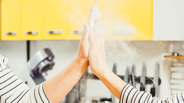 Foto cooperação culinária bem-sucedida closeup de mãos de mulheres dando cinco tirando farinha