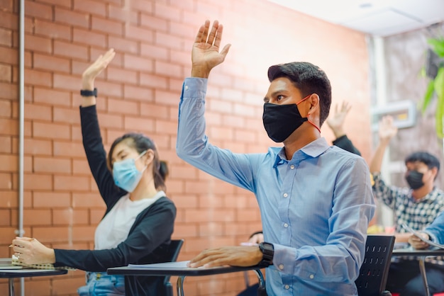 Cooperação empresarial: Jovem treinador ou palestrante asiático faz uma apresentação de flip chart para diversos empresários em uma reunião no escritório. O tutor ou formador masculino apresenta o projeto a diversos colegas.