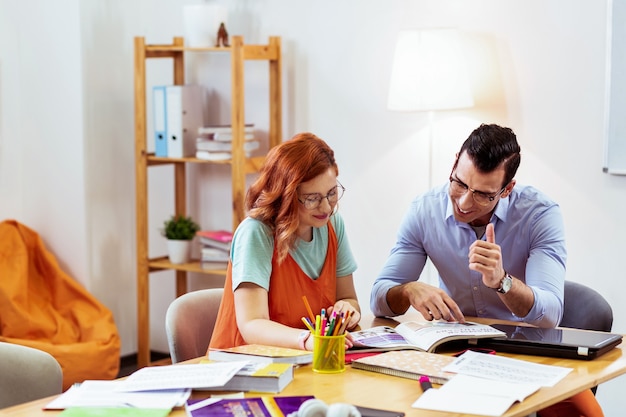 Cooperación productiva. Gente agradable alegre leyendo un libro juntos mientras aprenden nueva información