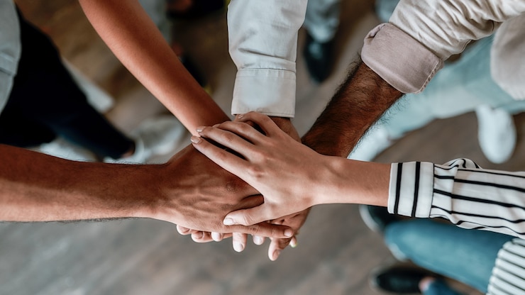 Foto cooperación. vista superior de personas cogidas de la mano juntas mientras está de pie en la oficina. trabajo en equipo